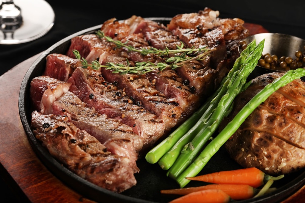 Tranchiertes Black-Angus-Steak mit Thymian und grünem Spargel